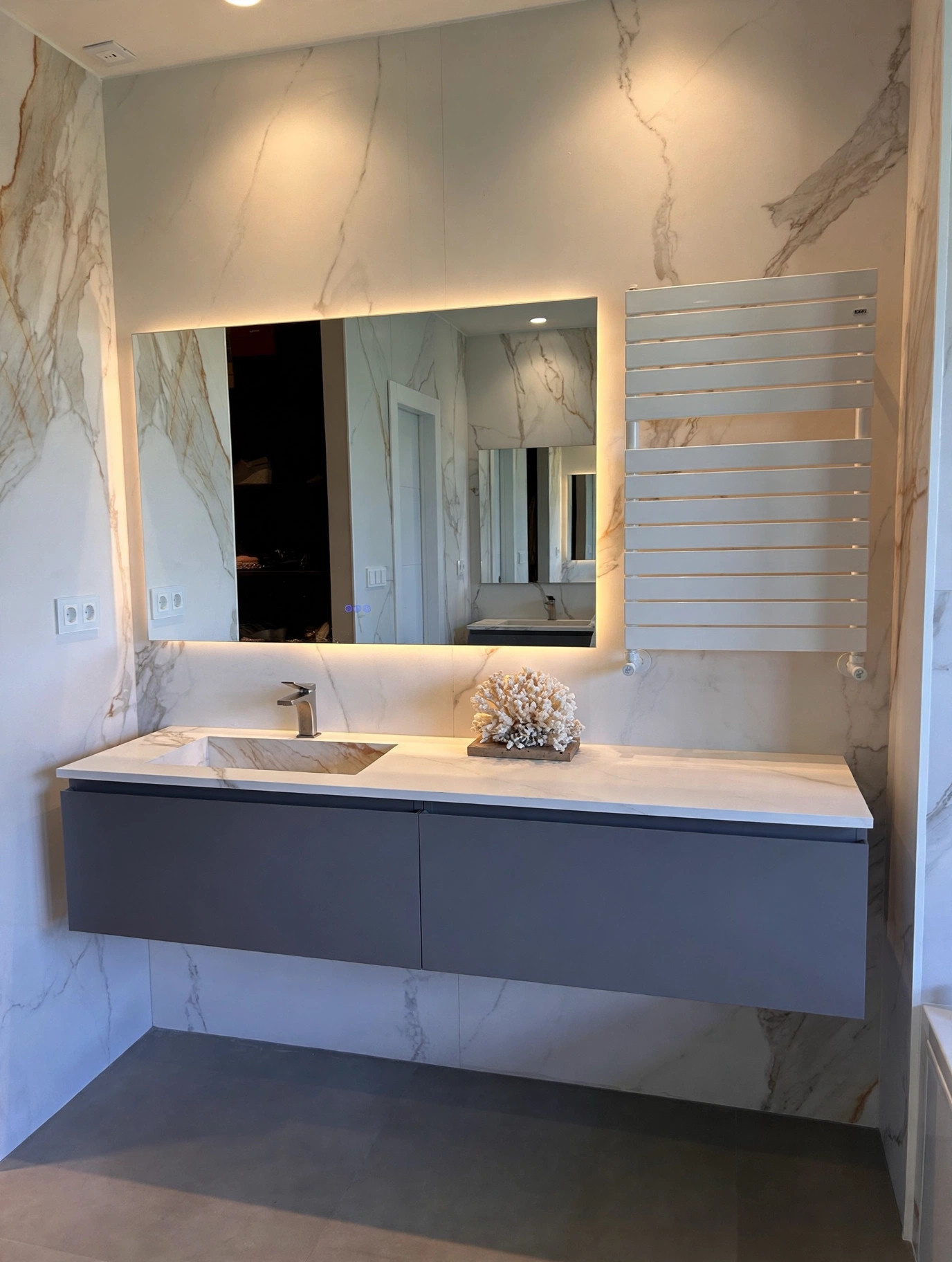 Baño principal revestido en piedra clara con bañera bajo la ventana